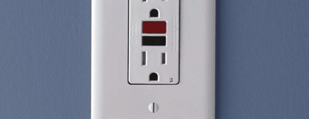 A white GFCI outlet installed on a blue wall, illustrating the importance of GFCI outlet replacement for electrical safety.