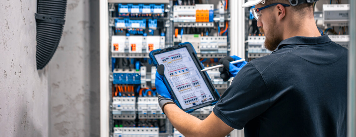 Electrician in Sebastopol inspecting an electrical panel using a digital tablet.